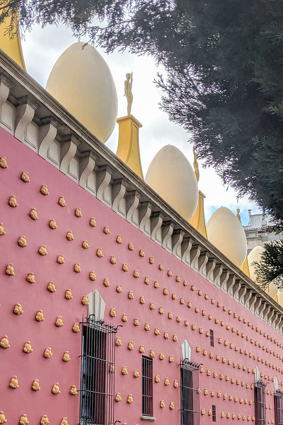 Exterior of the Salvador Dali Museum studded with plaster-covered croissants, and a roof topped with giant eggs and Oscars